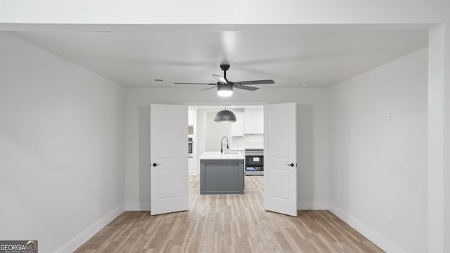 interior space with a sink, light wood-style flooring, and baseboards