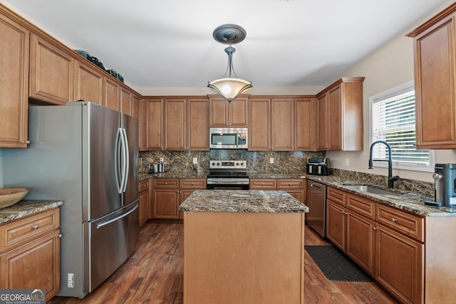 kitchen featuring stainless steel appliances, dark wood-type flooring, a kitchen island, and a sink