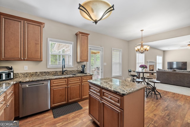 kitchen with open floor plan, stainless steel dishwasher, light wood-type flooring, and a sink