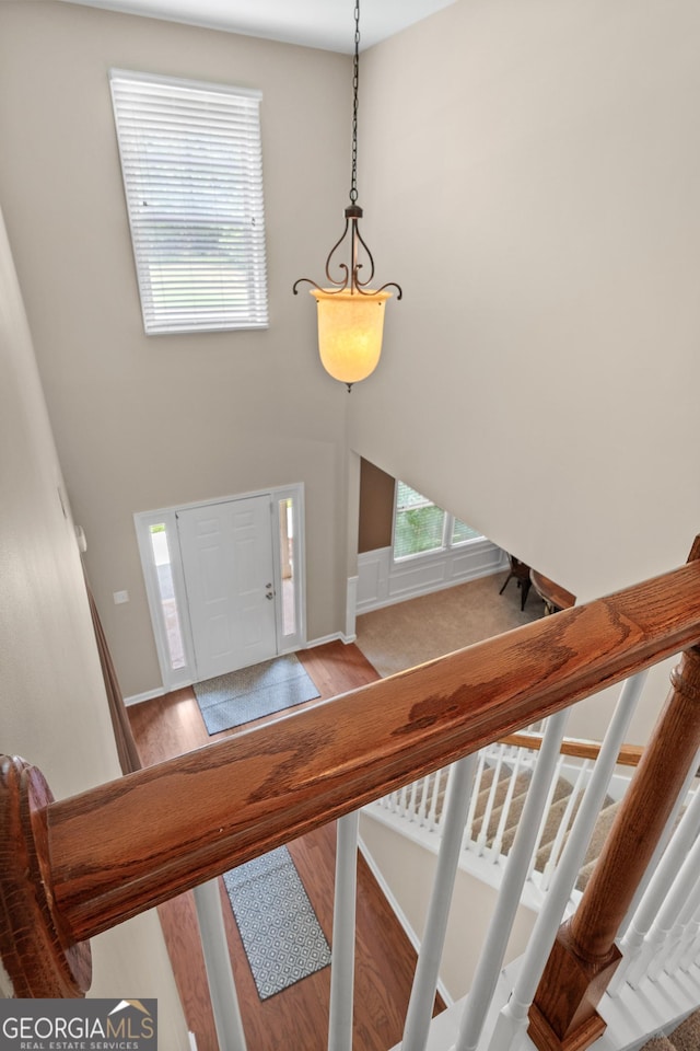 entryway with stairway, wood finished floors, a towering ceiling, and baseboards