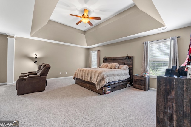 bedroom with carpet floors, visible vents, decorative columns, and a tray ceiling