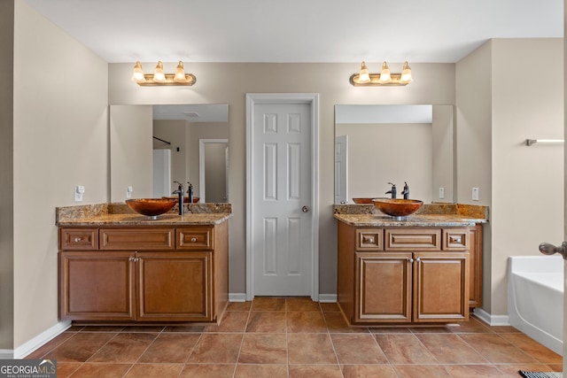 full bathroom featuring two vanities, a sink, a bathing tub, and baseboards