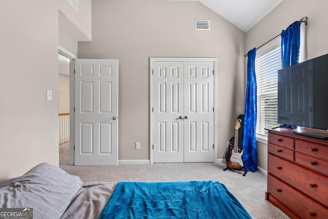 bedroom featuring lofted ceiling, carpet floors, visible vents, baseboards, and a closet