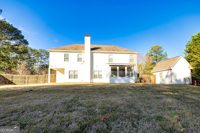 rear view of house with a yard, a chimney, fence, and a sunroom