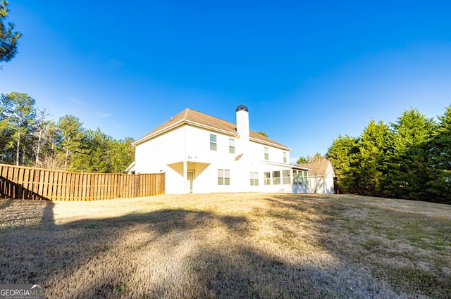 rear view of property with a yard, a chimney, and fence