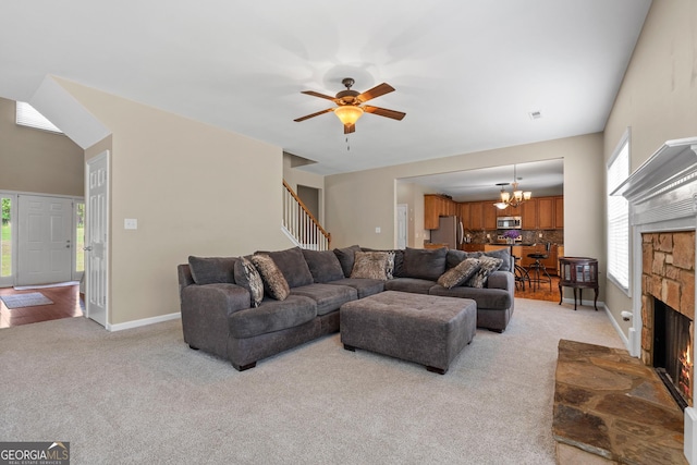 living area with light colored carpet, stairway, a stone fireplace, baseboards, and ceiling fan with notable chandelier