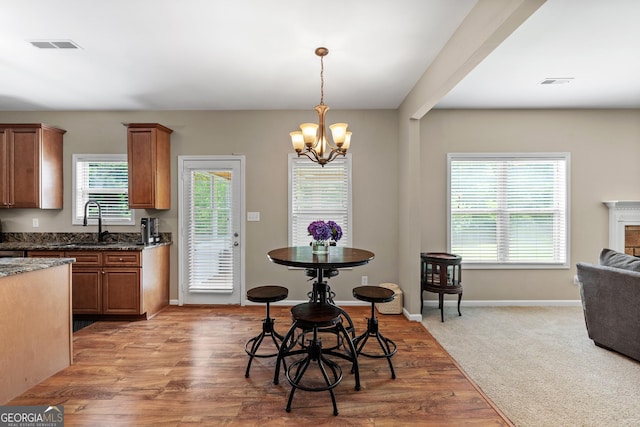 kitchen featuring plenty of natural light, a notable chandelier, brown cabinetry, and a sink