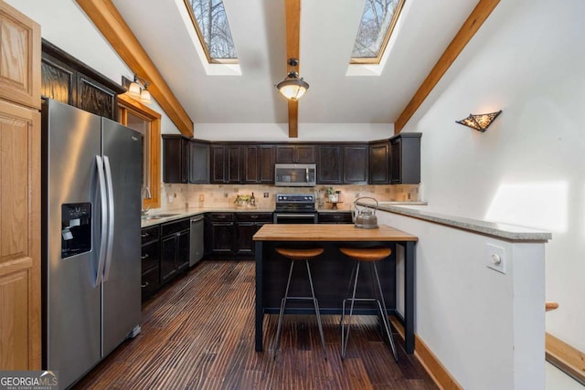 kitchen with stainless steel appliances, light countertops, a sink, and decorative backsplash