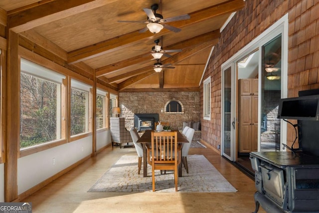 sunroom with vaulted ceiling with beams, ceiling fan, wood ceiling, and a wood stove