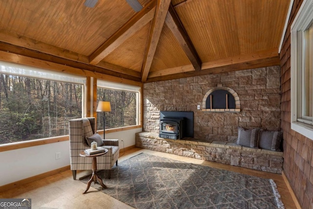 living area with a wood stove, vaulted ceiling with beams, wood ceiling, and baseboards