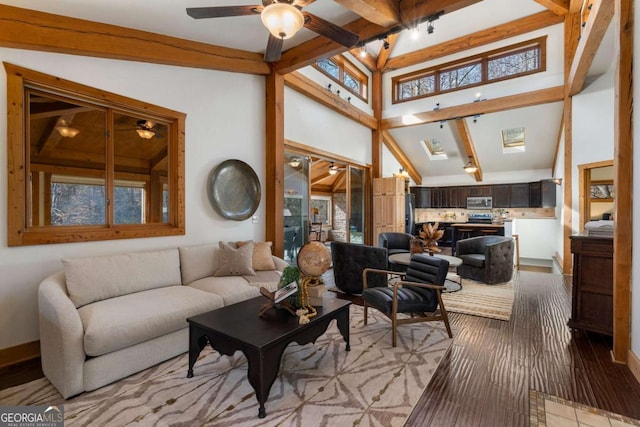 living room with a ceiling fan, a skylight, beamed ceiling, and high vaulted ceiling