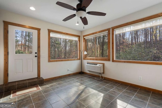 unfurnished sunroom featuring an AC wall unit and a ceiling fan