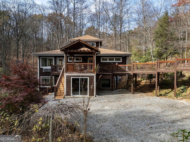 view of front of property with gravel driveway, a shingled roof, stairs, and a wooden deck