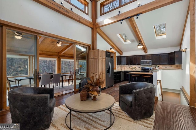 living area with a skylight, beam ceiling, high vaulted ceiling, and wood finished floors