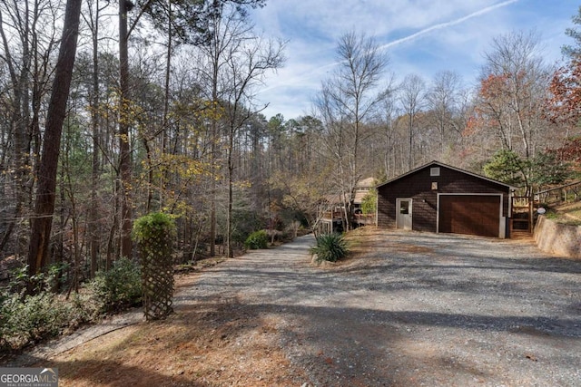 exterior space featuring driveway, a detached garage, and a forest view