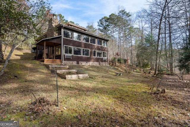 back of property featuring cooling unit, a garden, and a chimney