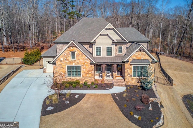 craftsman house featuring metal roof, a porch, stone siding, driveway, and a standing seam roof