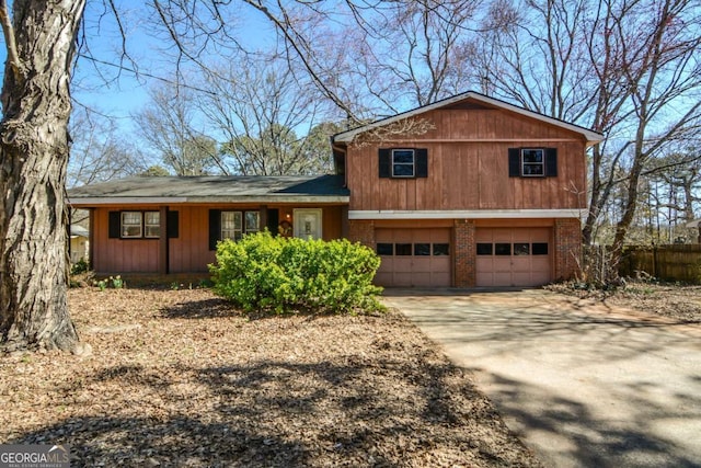 split level home with a garage, brick siding, and driveway