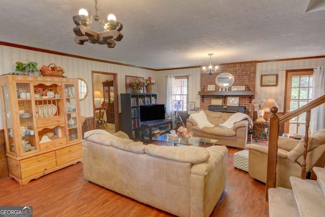 living room with stairs, a healthy amount of sunlight, wood finished floors, and an inviting chandelier