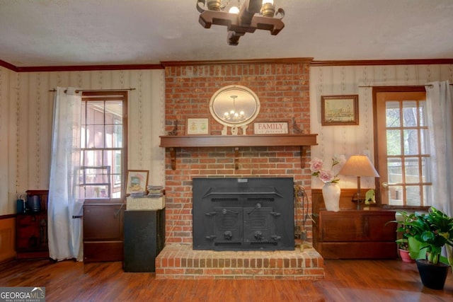 living area featuring crown molding, a fireplace, wood finished floors, and wallpapered walls