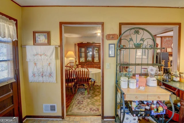 interior space with baseboards, visible vents, and ornamental molding