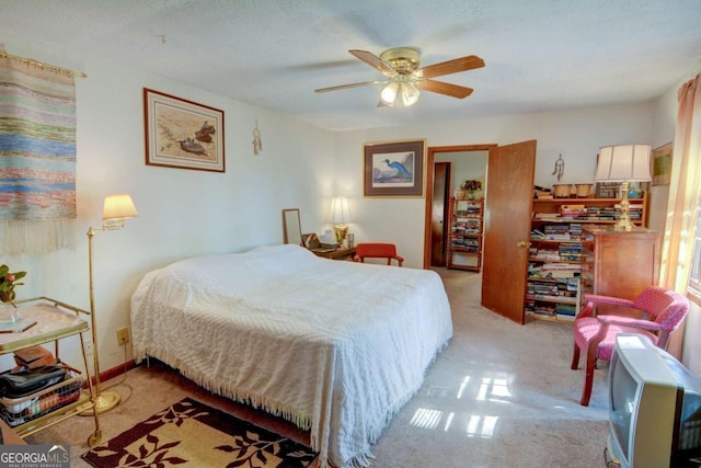 bedroom with a textured ceiling, a ceiling fan, and light colored carpet