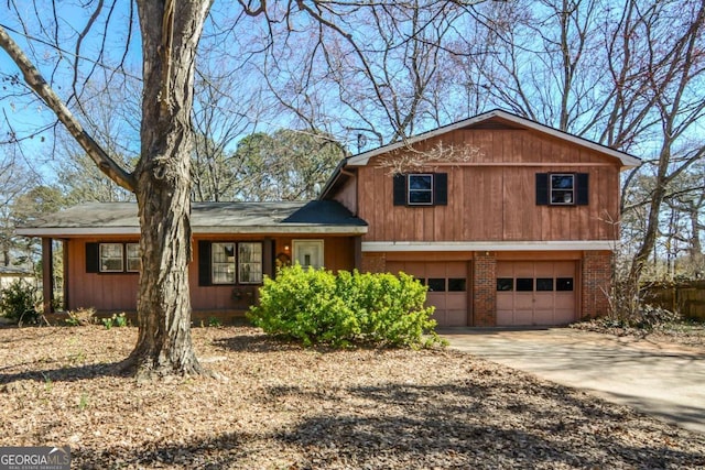 split level home featuring driveway, brick siding, and an attached garage