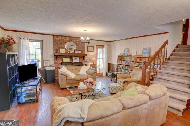 living room featuring wallpapered walls, stairway, a textured ceiling, and wood finished floors