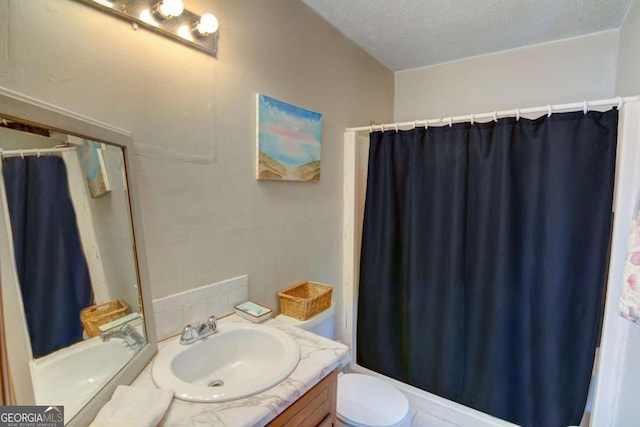 full bath with a textured ceiling, vanity, and toilet