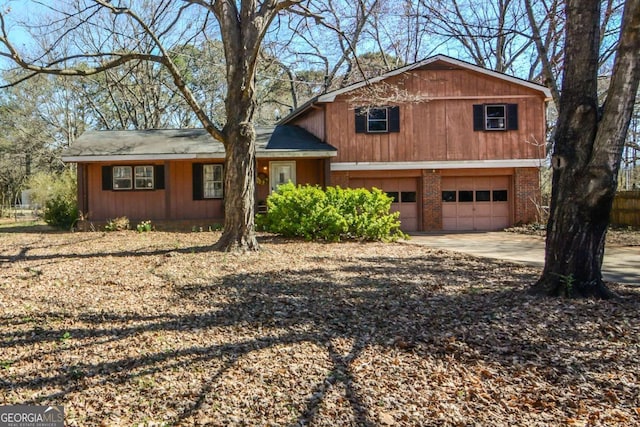 split level home featuring a garage, driveway, and brick siding