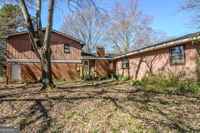 back of property featuring brick siding and a chimney