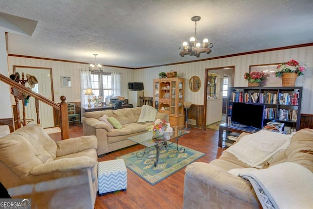 living room featuring a chandelier, a textured ceiling, wood finished floors, and wallpapered walls