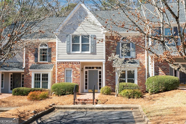 view of front facade with a shingled roof and brick siding