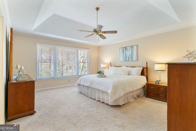 carpeted bedroom featuring baseboards, ornamental molding, a raised ceiling, and a textured ceiling