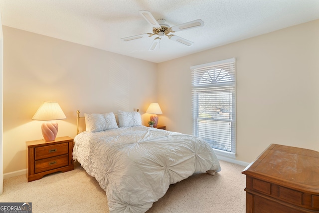 bedroom featuring light carpet, ceiling fan, a textured ceiling, and baseboards