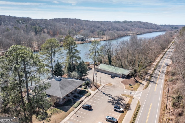 birds eye view of property featuring a water view and a wooded view