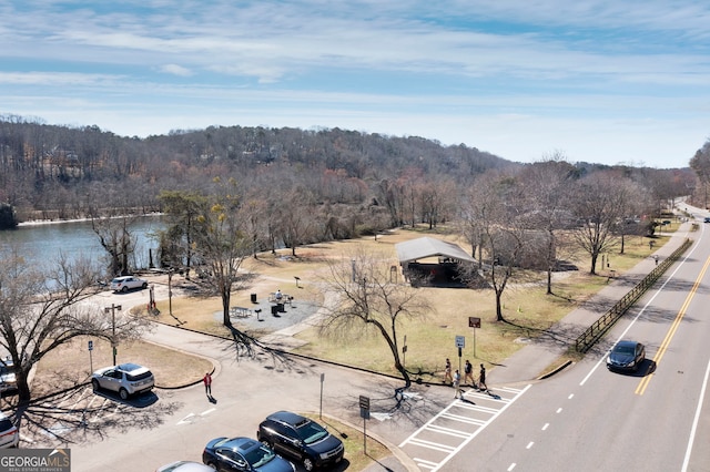 birds eye view of property featuring a water view and a wooded view