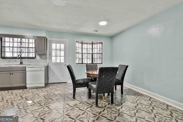 dining room with a textured ceiling, light floors, and baseboards