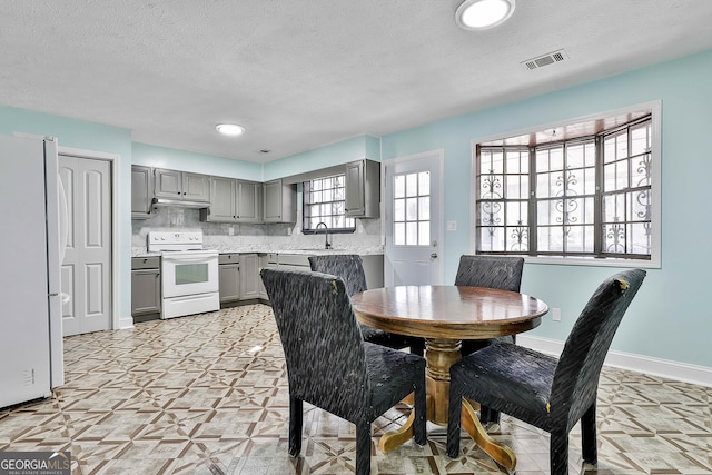 dining area featuring visible vents, baseboards, and a textured ceiling