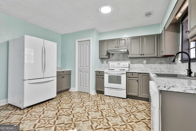 kitchen with under cabinet range hood, white appliances, a sink, visible vents, and backsplash