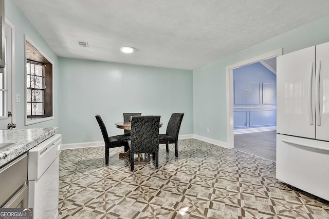 dining space featuring visible vents, a textured ceiling, and baseboards