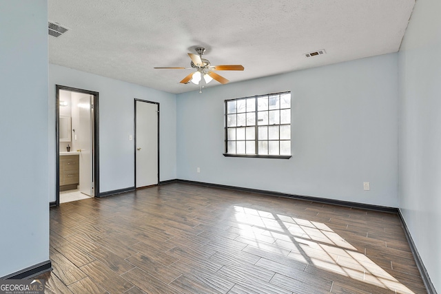 unfurnished bedroom with a textured ceiling, dark wood-style flooring, visible vents, and baseboards