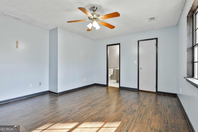 unfurnished bedroom with ensuite bath, baseboards, visible vents, and dark wood finished floors