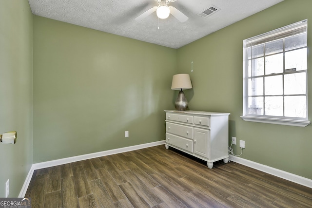 unfurnished bedroom featuring baseboards, a textured ceiling, visible vents, and dark wood-type flooring