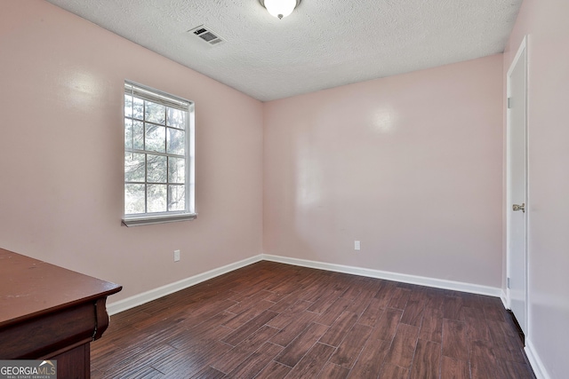 spare room featuring dark wood-style floors, a textured ceiling, visible vents, and baseboards