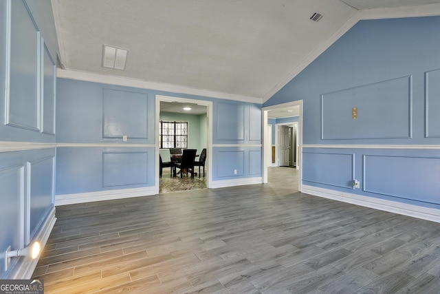 unfurnished living room with vaulted ceiling, visible vents, and a decorative wall