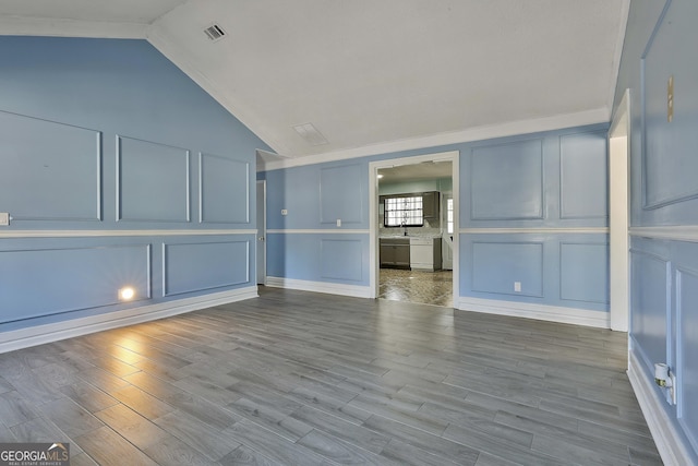 unfurnished living room with vaulted ceiling, light wood-style flooring, visible vents, and a decorative wall