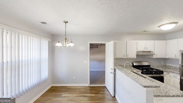 kitchen with white cabinets, range, light stone counters, under cabinet range hood, and pendant lighting