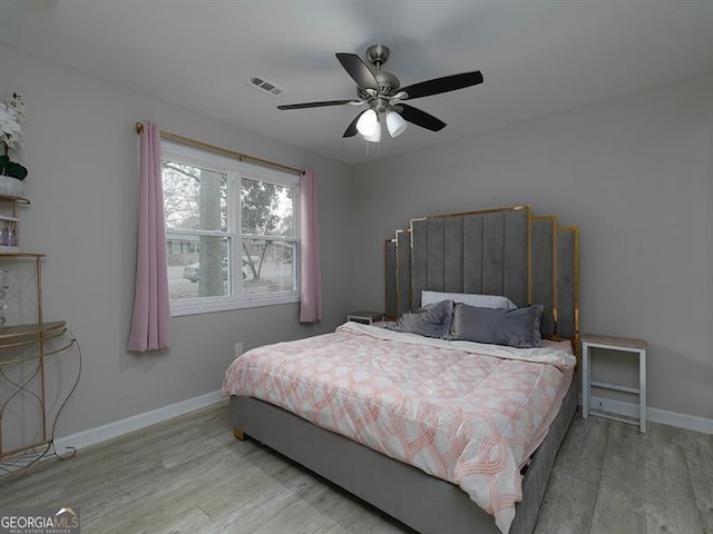 bedroom with visible vents, ceiling fan, baseboards, and wood finished floors