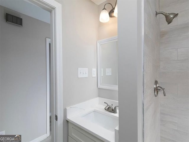 full bathroom featuring visible vents, vanity, and tiled shower